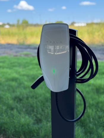 A tesla charging station is mounted on a pole.